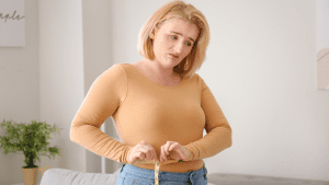 gut health and weight gain are connected, women measuring her waist looking upset and uncomfortable